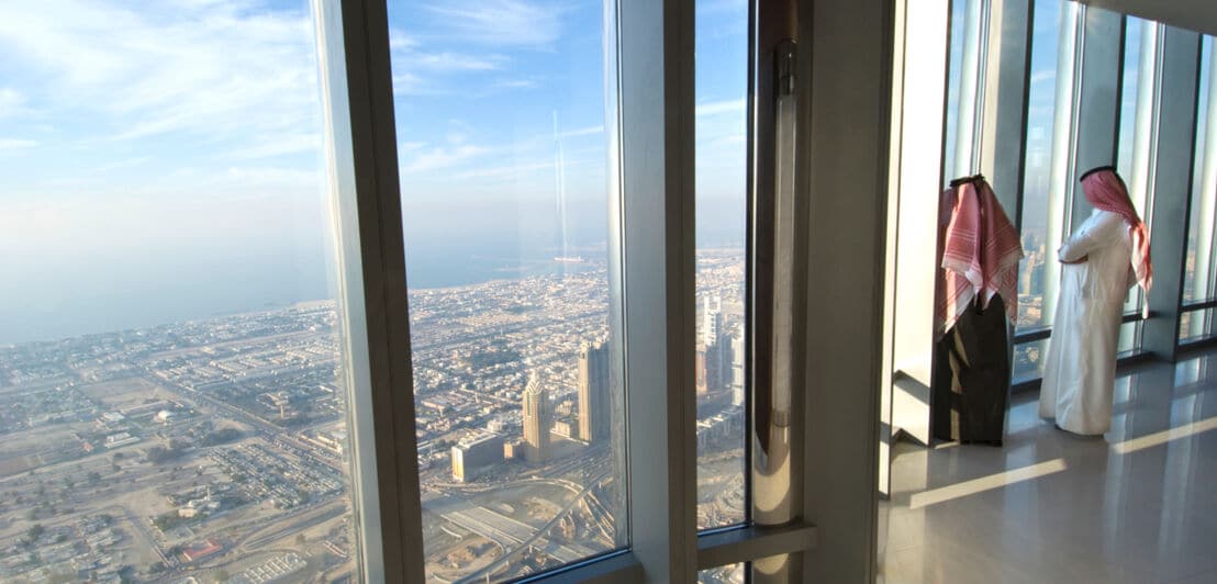 Zwei Männer stehen am Fenster und blicken über Dubai