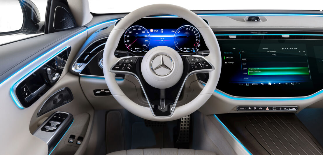 Das Cockpit einen Mercedes mit hellem Lenkrad, heller Verkleidung und großem Display