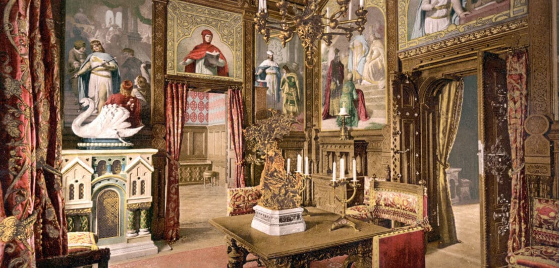 Historische, kolorierte Fotoaufnahme eines prunkvollen Speisezimmers mit eichenvertäfelten Wandgemälden und vergoldeten Textilien