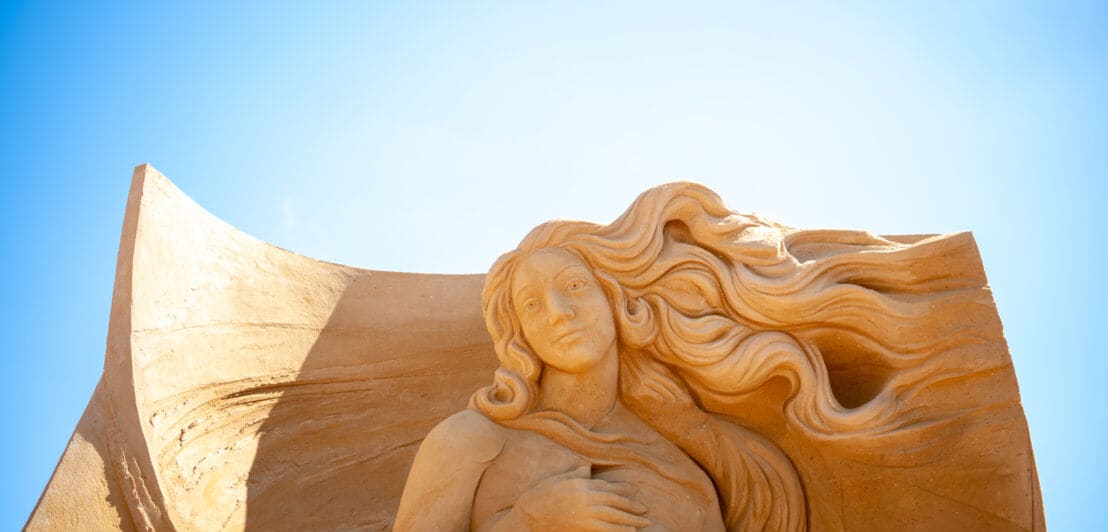 Große Sandskulptur, die eine Frau mit wallendem Haar zeigt