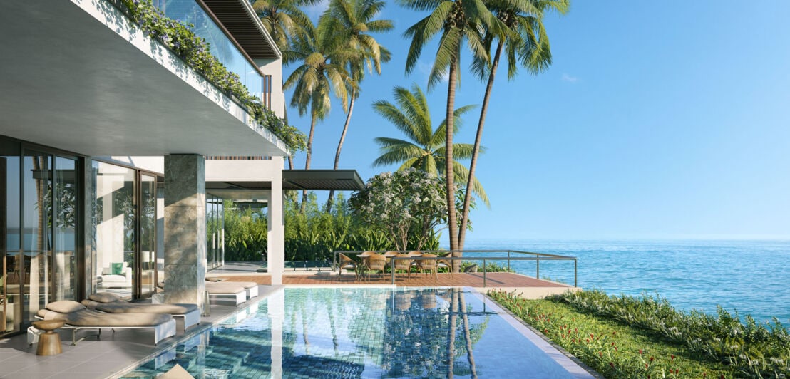 Terrasse einer luxuriösen Hotelsuite mit Swimmingpool und Palmen am Meer.