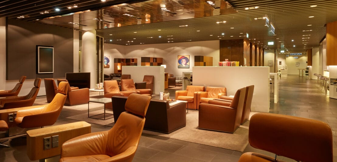 Eine weitläufige, luxuriöse Flughafen-Lounge mit cognacfarbenen Ledersesseln