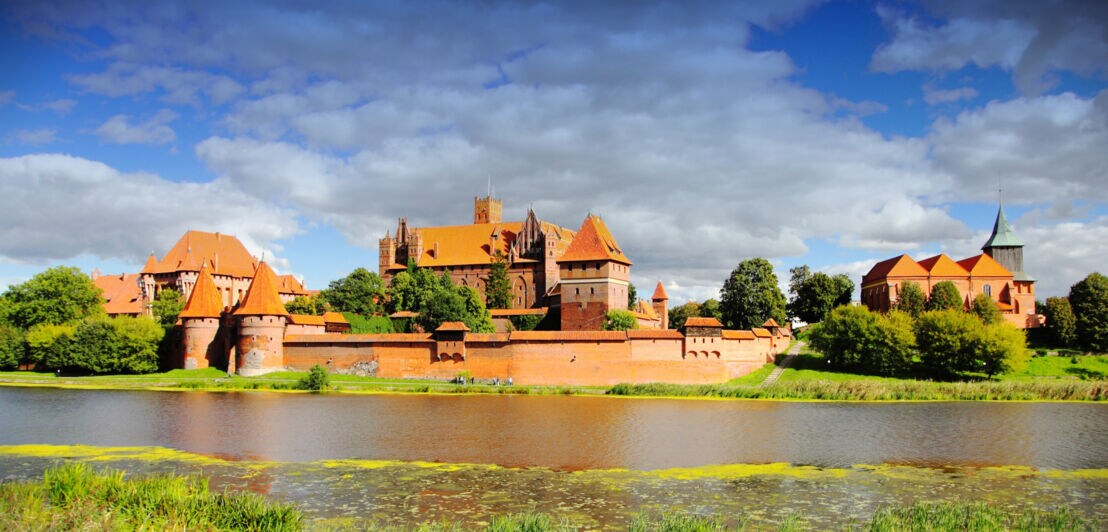 Eine aus Backsteinen erbaute Burganlage an einem Fluss
