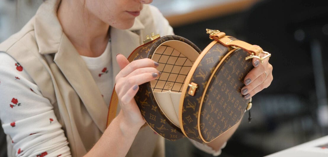 Eine Frau kontrolliert eine braune, runde Lederhandtasche mit Tumbler-Schloss von Louis Vuitton