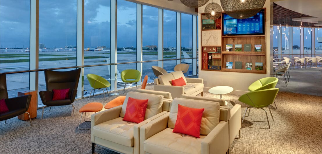 Moderne Flughafenlounge mit bodentiefen Panoramafenstern und Blick aufs Rollfeld.