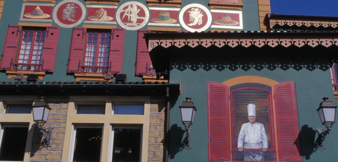 Wandgemälde mit einem Porträt von Koch Paul Bocuse an der Fassade eines Restaurants mit bunten Ornamenten