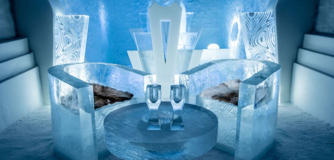 Ein Raum in einem Eishotel mit Sesseln und Geschirr aus Eis.