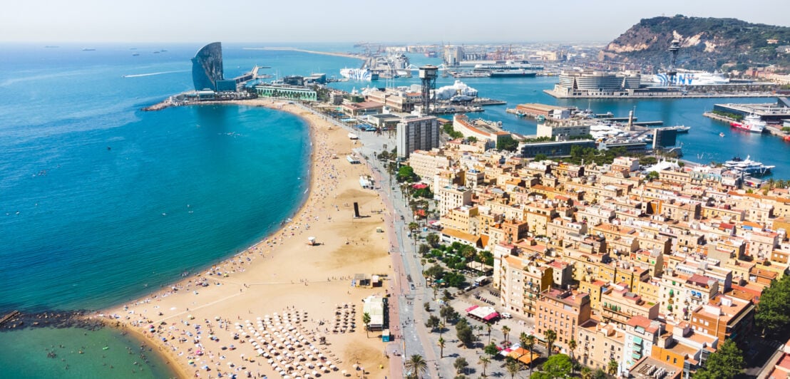 Luftaufnahme eines Stadtteils zwischen Strand und Hafen auf einer Landzunge in Barcelona.