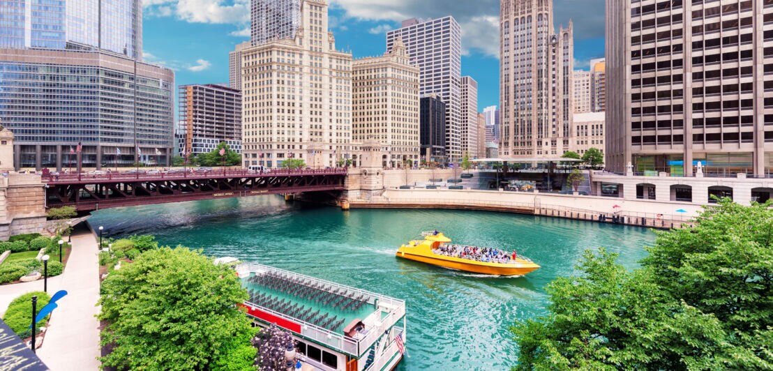 Ein gelbes Ausflugsboot auf dem Chicago River vor der Skyline Chicagos.