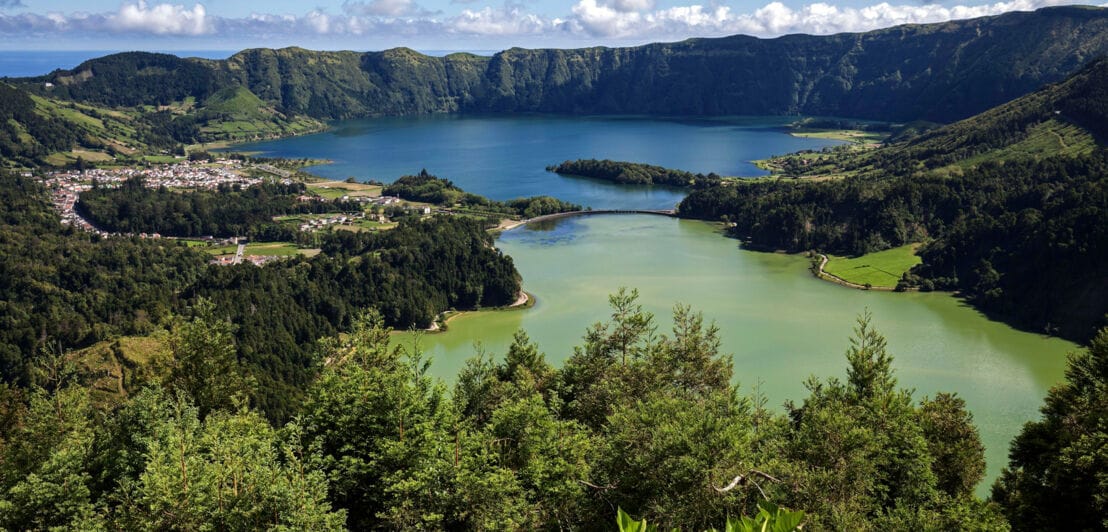 Landschaftpanorama von zwei miteinander verbundenen Kraterseen mit blauem und grünem Wasser.