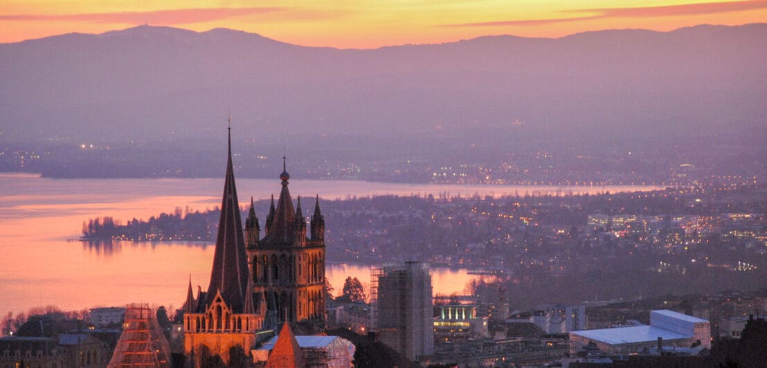 Luftaufnahme von Lausanne am Abend, mit Kathedrale Notre-Dame im Vordergrund.