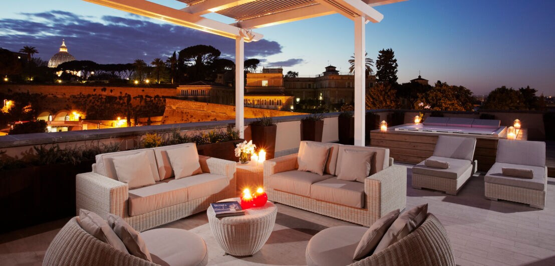 Eine Hotelterrasse mit Sitzgelegenheiten im Stadtzentrum Roms bei Nacht.