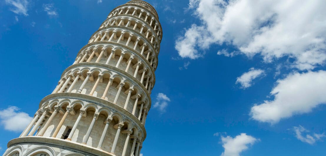 Der Schiefe Turm von Pisa vor blauem Himmel mit Wolken aus der Froschperspektive.