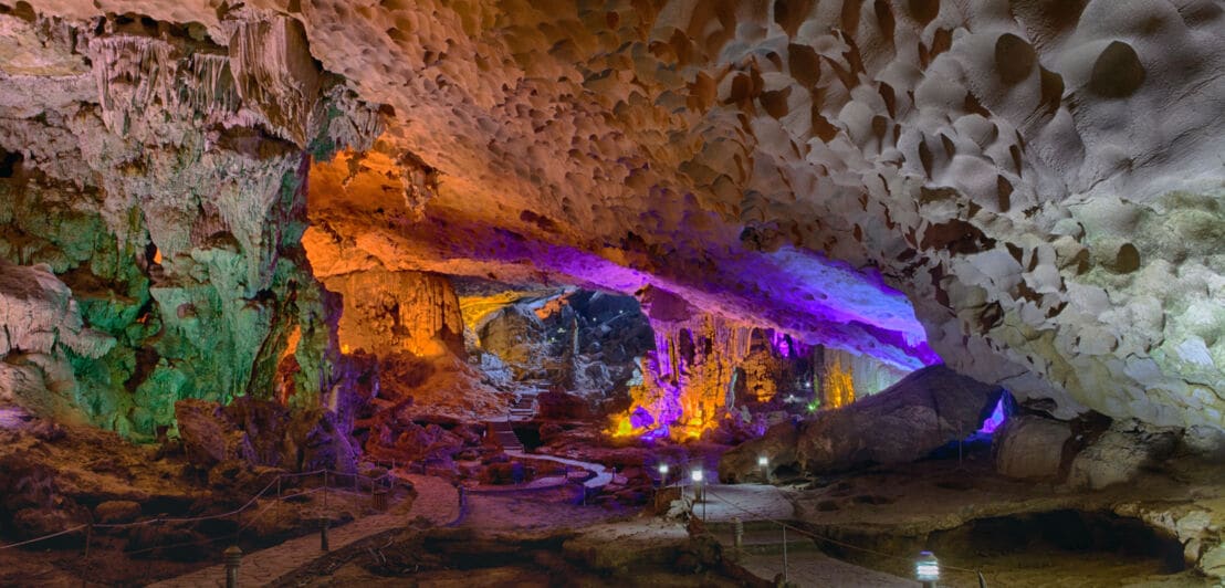 Eine in verschiedenen Farben beleuchtete Tropfsteinhöhle.