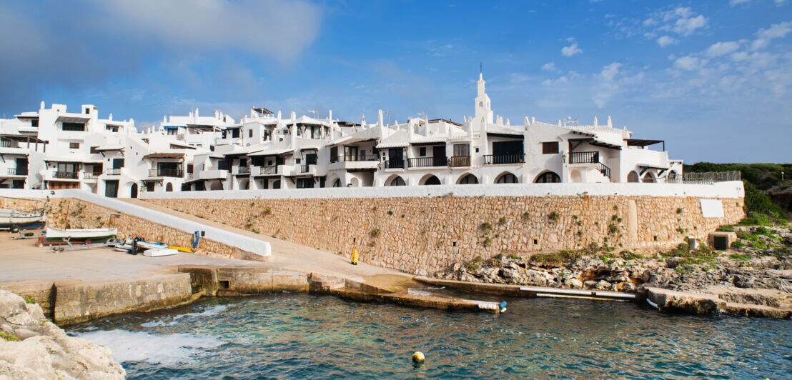 Viele kleine Häuser mit weißen Fassaden an der Küste Menorcas.