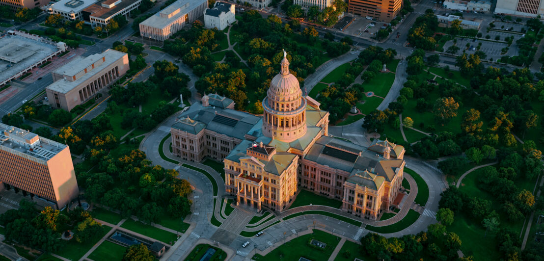 Luftaufnahme des Texas State Capitol, umgeben von einer Parklandschaft im Stadtzentrum Austins.