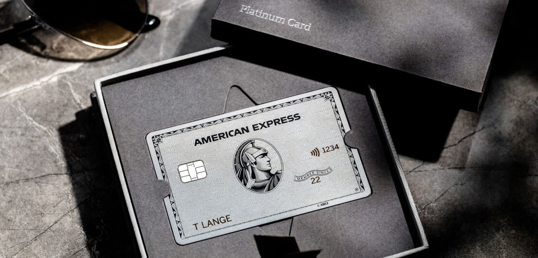Eine Amex Platin-Kreditkarte in einer eleganten, grauen Schachtel.