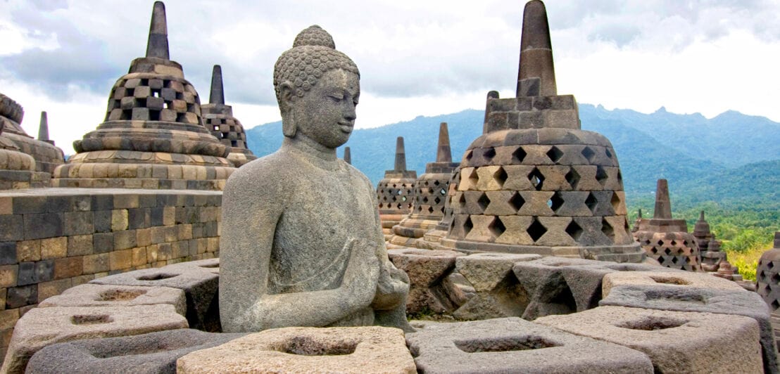 Buddhastatue und glockenförmige Gebilde der indonesischen Tempelanlage Borobudur.