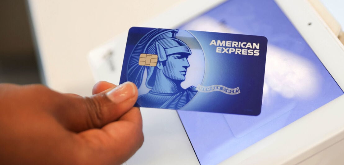 Eine American Express Blue Card bei der kontaktlosen Zahlung an einem Kassenterminal.