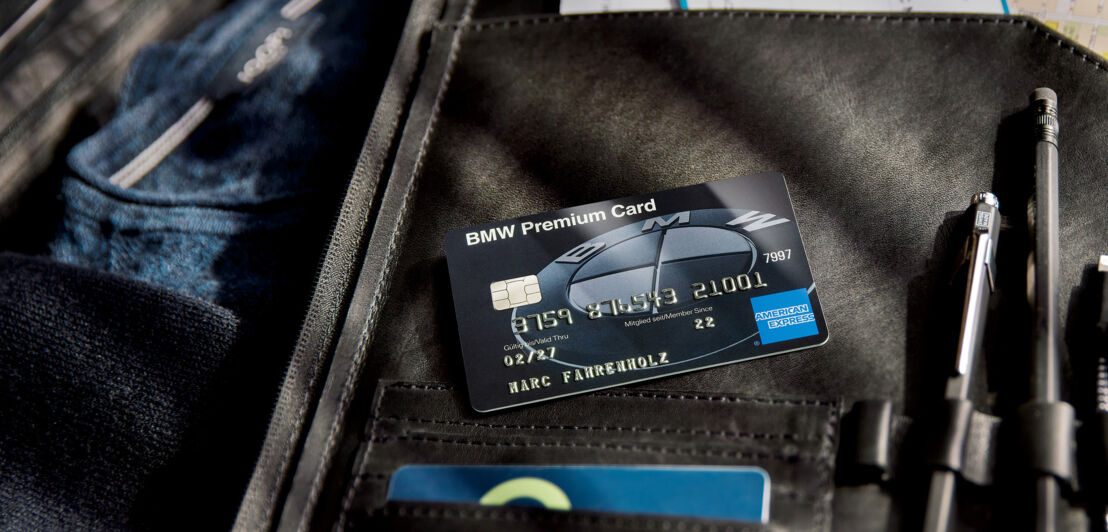 Eine schwarze BMW Premium Kreditkarte von American Express auf einem geöffneten Koffer.