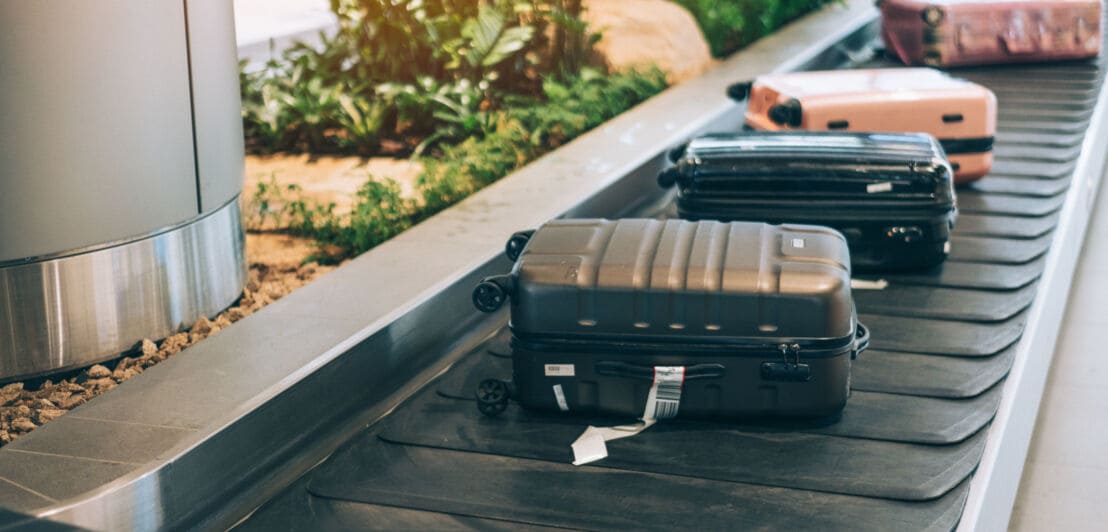 Mehrere Koffer, die auf einem Kofferband am Flughafen liegen.