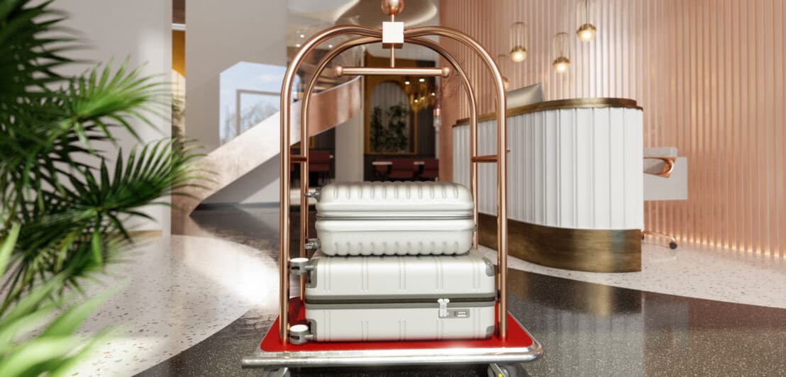 Ein Trolley in einer Hotellobby, auf dem zwei silberne Hartschalenkoffer liegen.