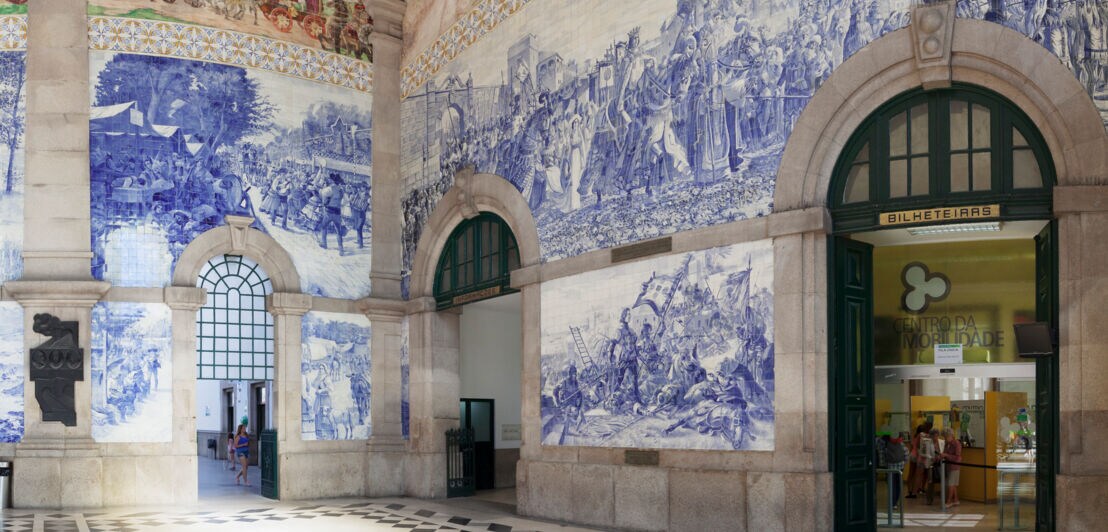 Eingangshalle des Bahnhofs São Bento in Porto, dessen Wände mit blau-weißen Keramikfliesen verziert sind.