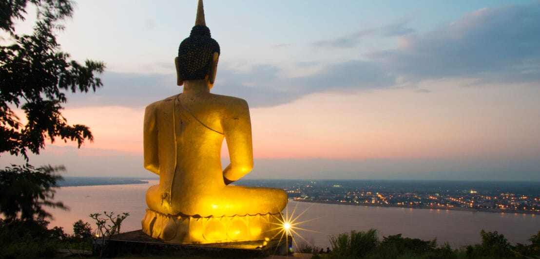 Rückansicht einer großen goldene Buddha-Statue auf einem Hügel in Pakse, Laos.