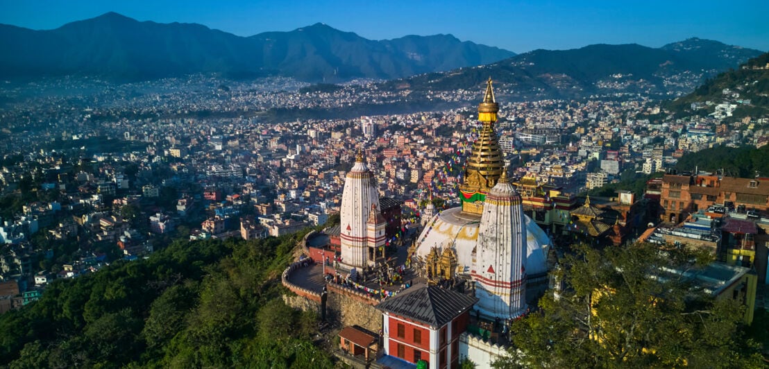 Buddhistische Tempelanlage auf einem Hügel vor Stadtpanorama von Kathmandu.