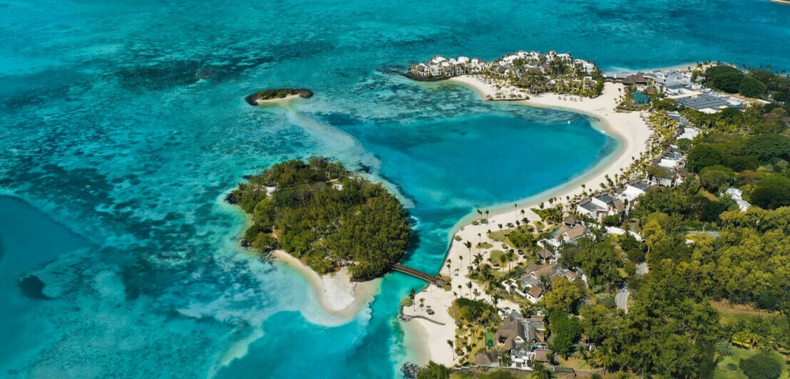 Ein luxuriöses Urlaubsresort mit Strandvillen an einer tropischen Lagune mit türkisblauem Wasser.