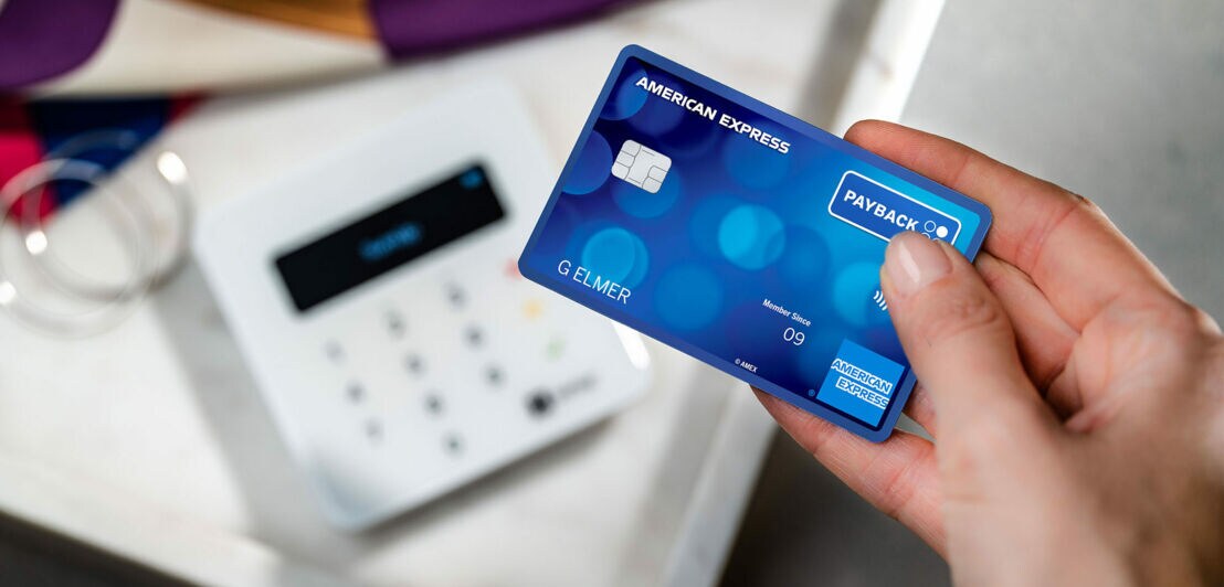 Kontaktlose Zahlung mit einer blauen Payback American Express Karte an einem Kartenlesegerät in einer Boutique.