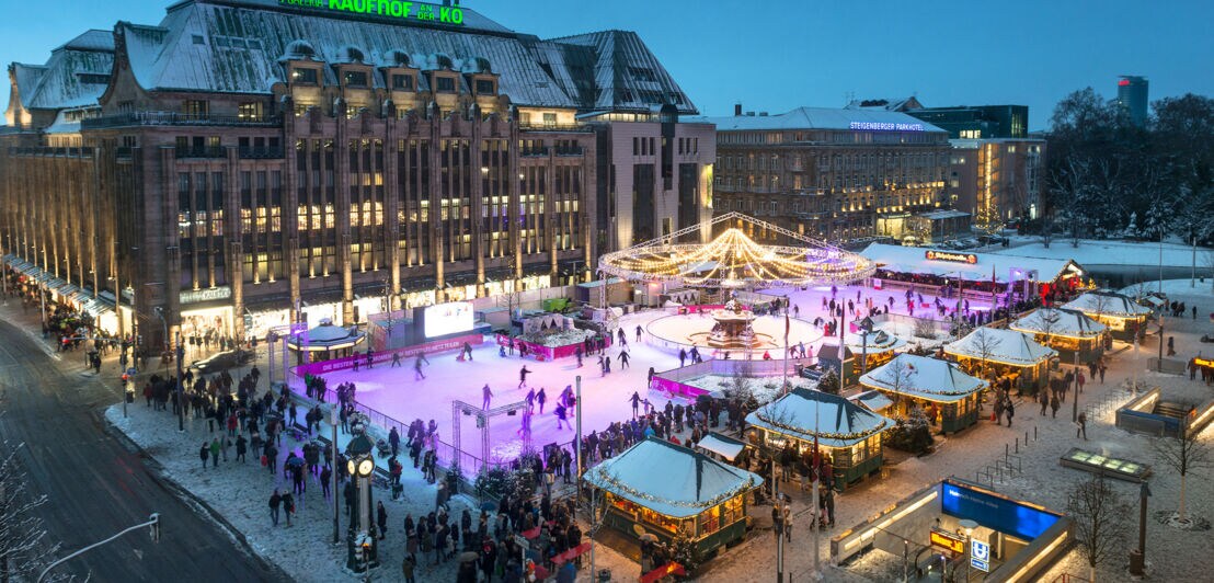 Belebte Eislaufbahn auf einer Einkausstraße im Stadtzentrum am Abend.