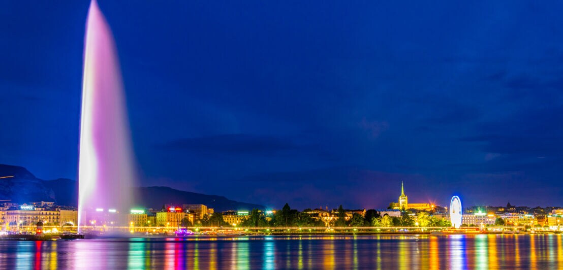 Wasserfontäne in Genf bei Nacht und bunt angeleuchtet.