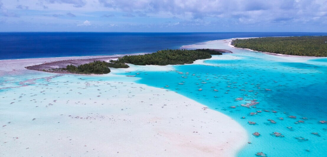 Kleine, flache Inseln mit grüner Vegetation, umgeben von Lagunenlandschaft.