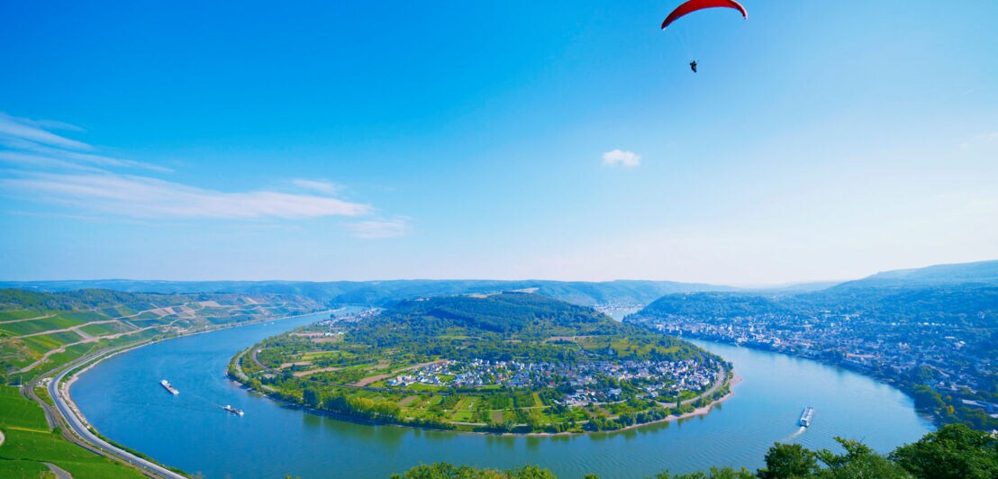 Panoramaaufnahme der Rheinschleife bei Boppard, über die eine Person mit Gleitschirm in der Ferne schwebt