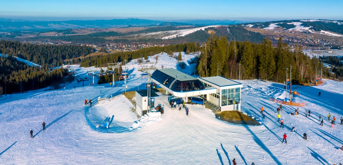 Menschen auf Ski und Snowboards auf der Skipiste am Berg Jankulakowski Wierch