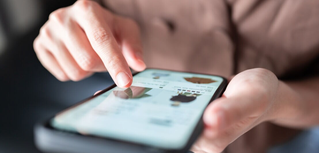 Nahaufnahme von einem Smartphone beim Online-Shopping in den Händen einer Person.
