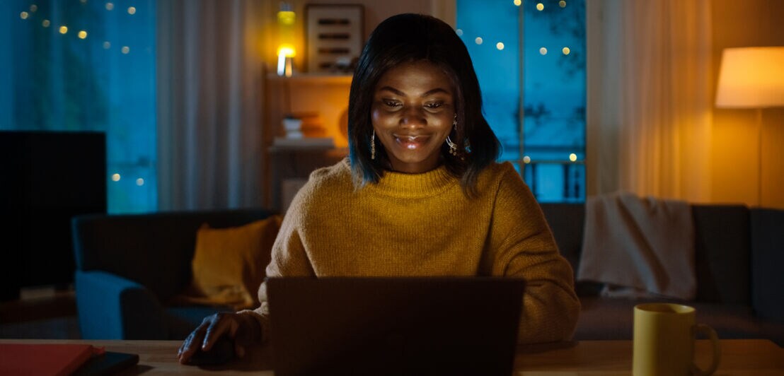 Eine Frau arbeitet nachts zu Hause am Laptop.