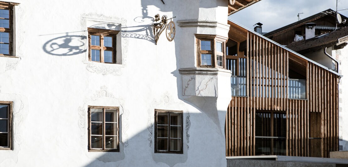 Gebäudekomplex mit weißer, historischer Fassade und moderner Architektur mit Holzdetails.