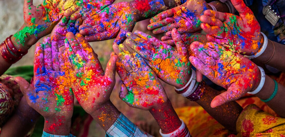 Hände voll bunter Farbe während eines Holi Festivals.