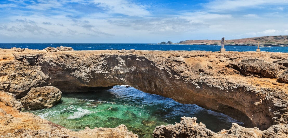 Blick auf eine Felsformation, die wie eine kleine Brücke übers Meer geht.