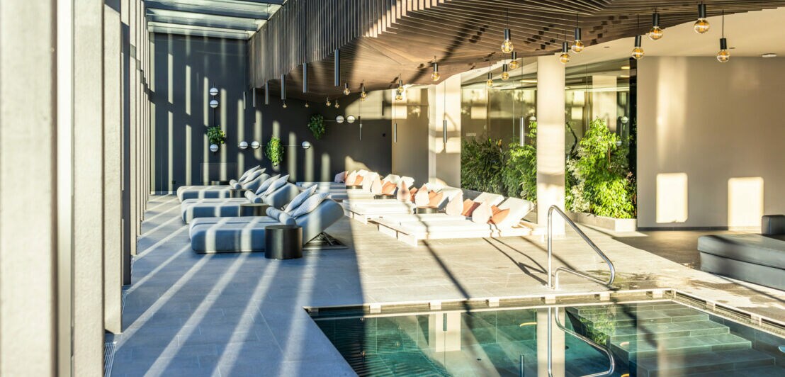 Großzügiger Spa-Bereich mit Pool, Liegen und viel Tageslicht.
