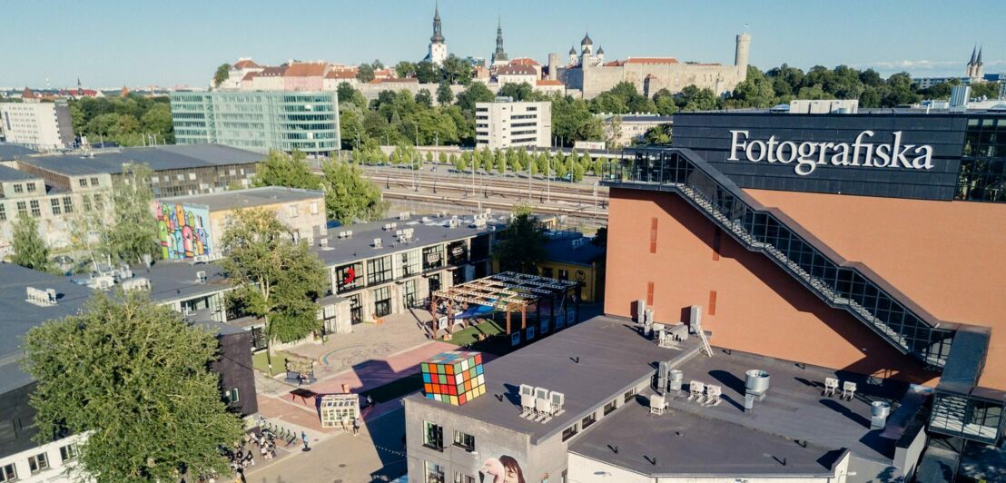 Blick auf den Gebäudekomplex Telliskivi in Tallin bei Dämmerung, im Hintergrund die Stadtmauer und Altstadt.