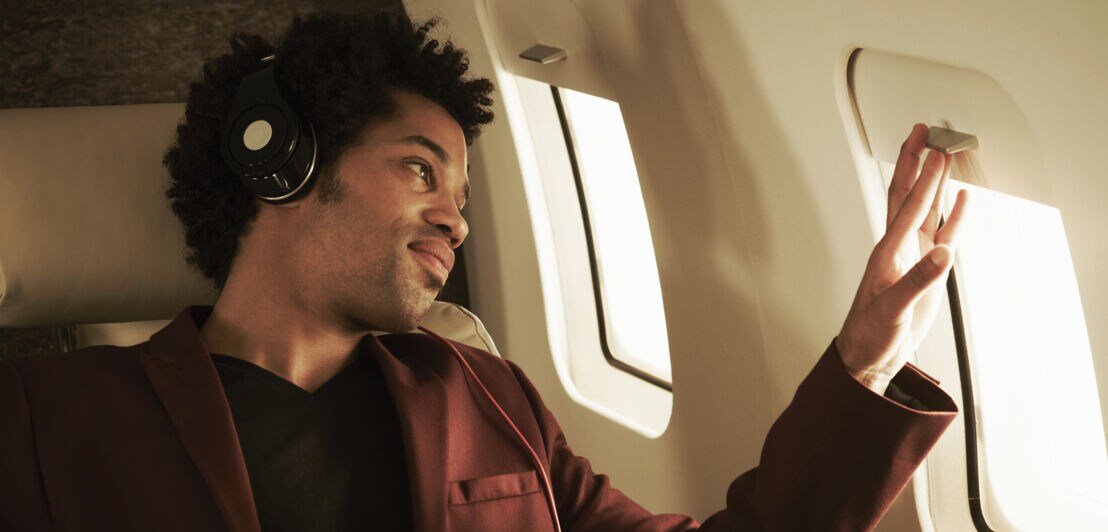 Fluggast mir Kopfhörern schaut aus dem Fenster.