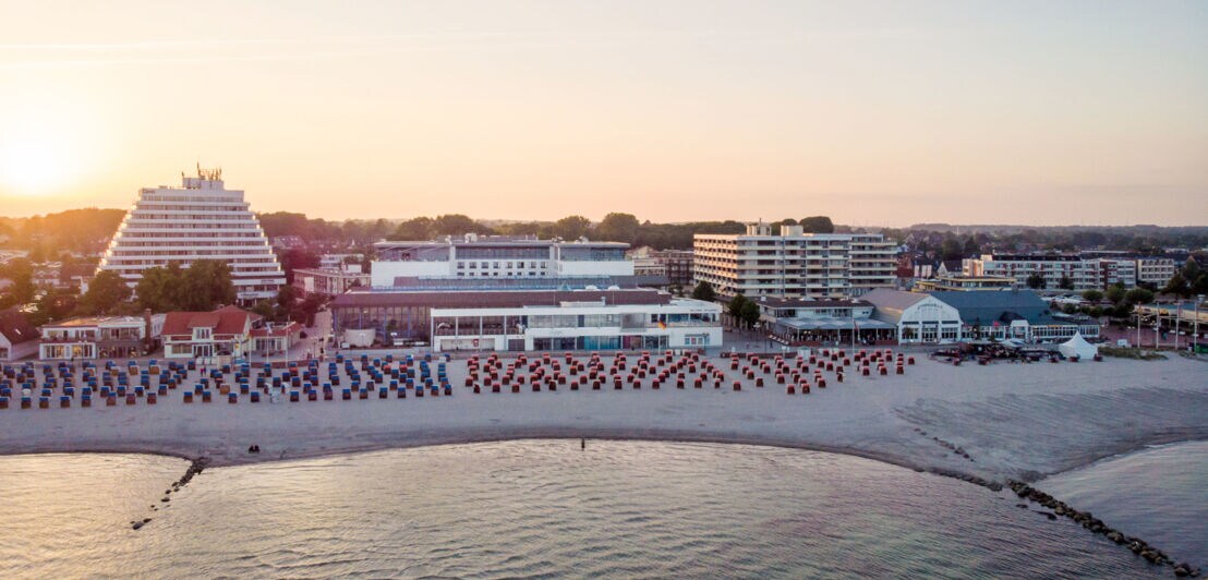 Luftaufnahme eines Hotelkomplexes mit Sandstrand am Meer bei Abenddämmerung.