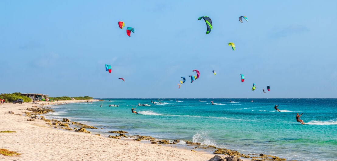 Zahlreiche Kitesurfende im türkisblauen Meer.
