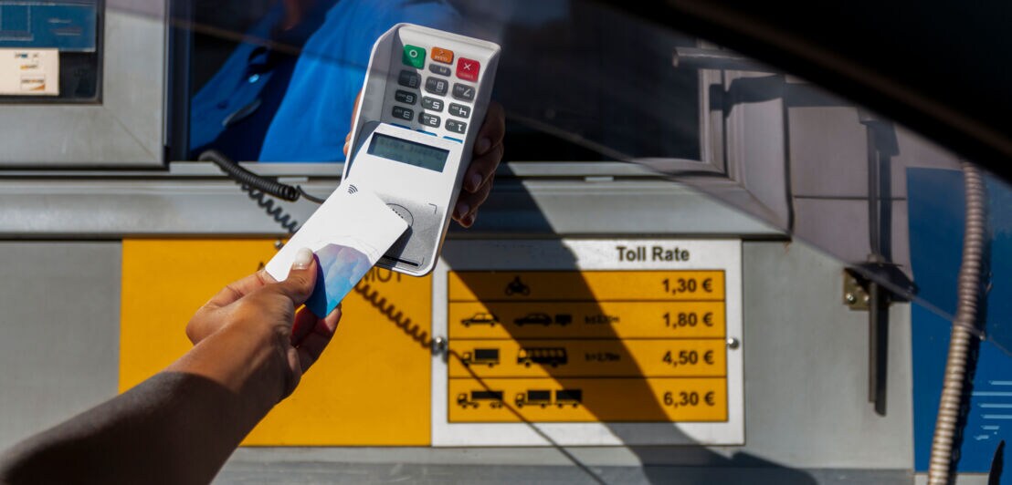 Kontaktlose Zahlung mit Kreditkarte bei einer Person an einer Mautstelle.