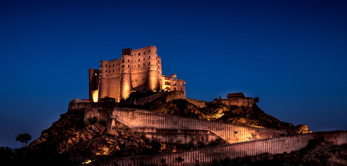 Beleuchtete Festung auf einem Hügel bei Nacht vor klarem, dunklem Himmel