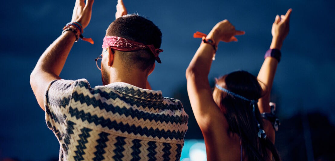 Zwei Personen im Vintage-Look, die von hinten zu sehen sein, klatschen und halten die Arme hoch.