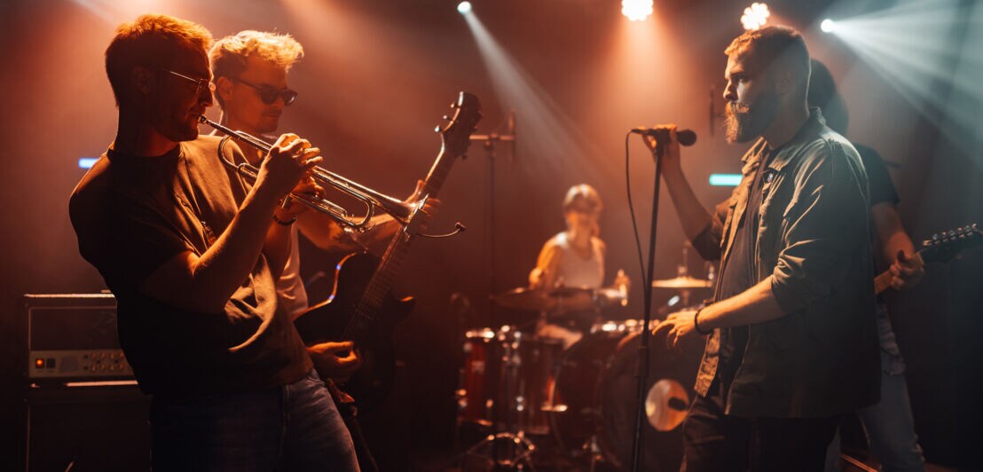 Musiker:innen spielen und singen auf einer Bühne.